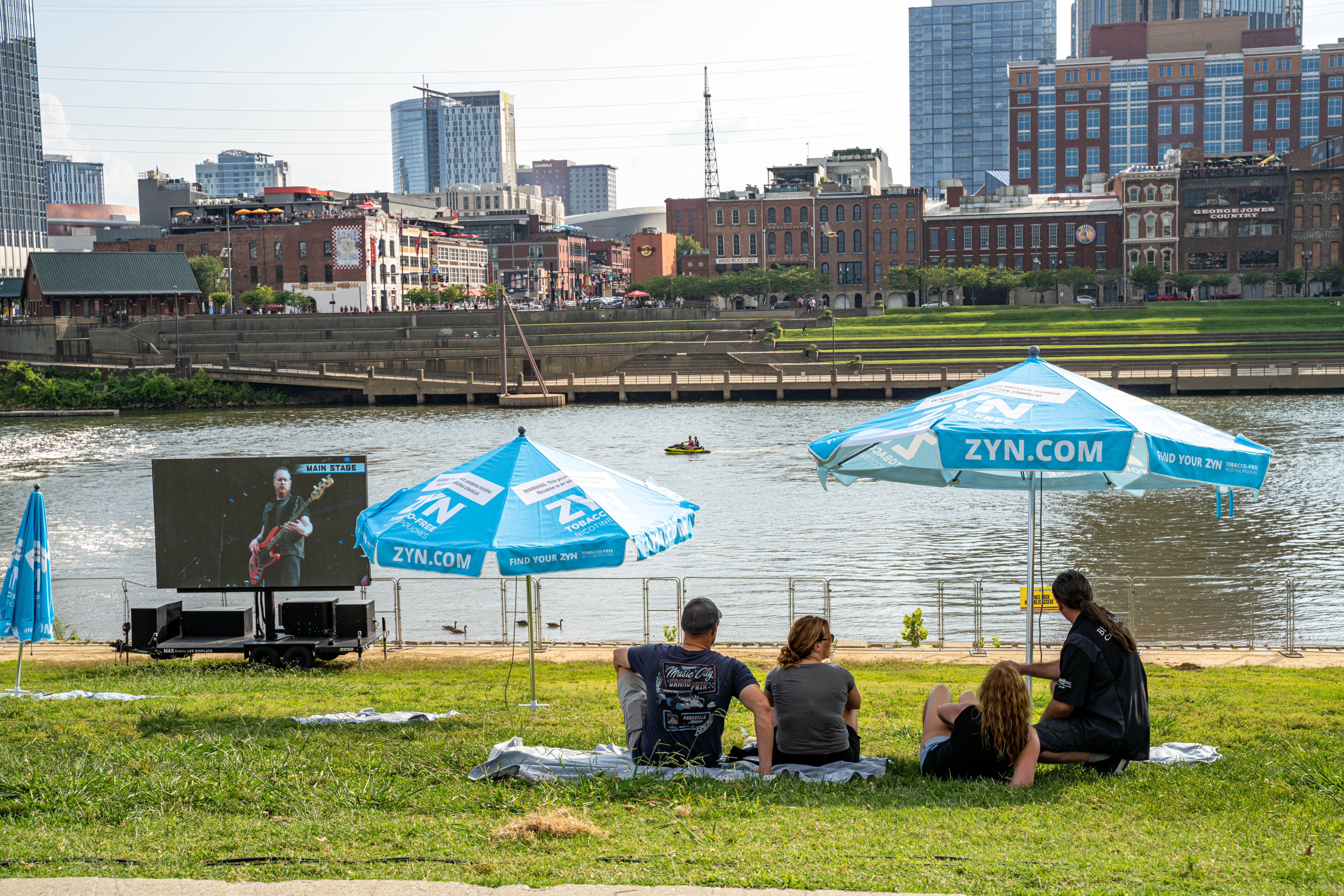 People sitting under blue ZYN umbrellas